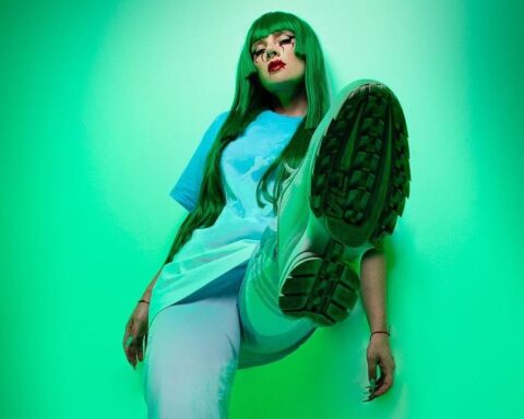 Entrópica con cabello verde y fondo del mismo color alzando el pie izquierdo