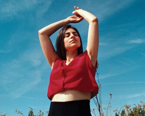 Dariana López con una blusa roja y alzando los brazos