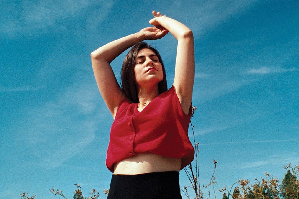 Dariana López con una blusa roja y alzando los brazos