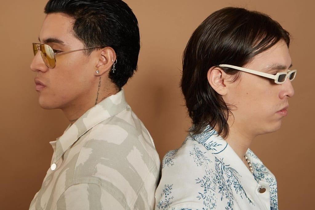 Los Inzul posando de espalda contra espalda en un fondo marrón