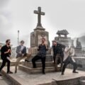 La banda peruana Perros Santos sosteniendo botellas de champagne en un cementerio de Lima