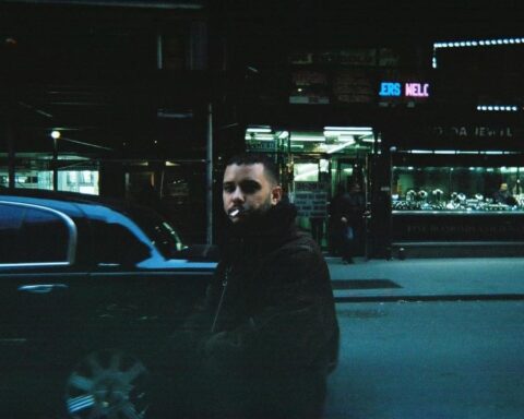 Jimmy Whoo caminando en una calle con un abrigo puesto