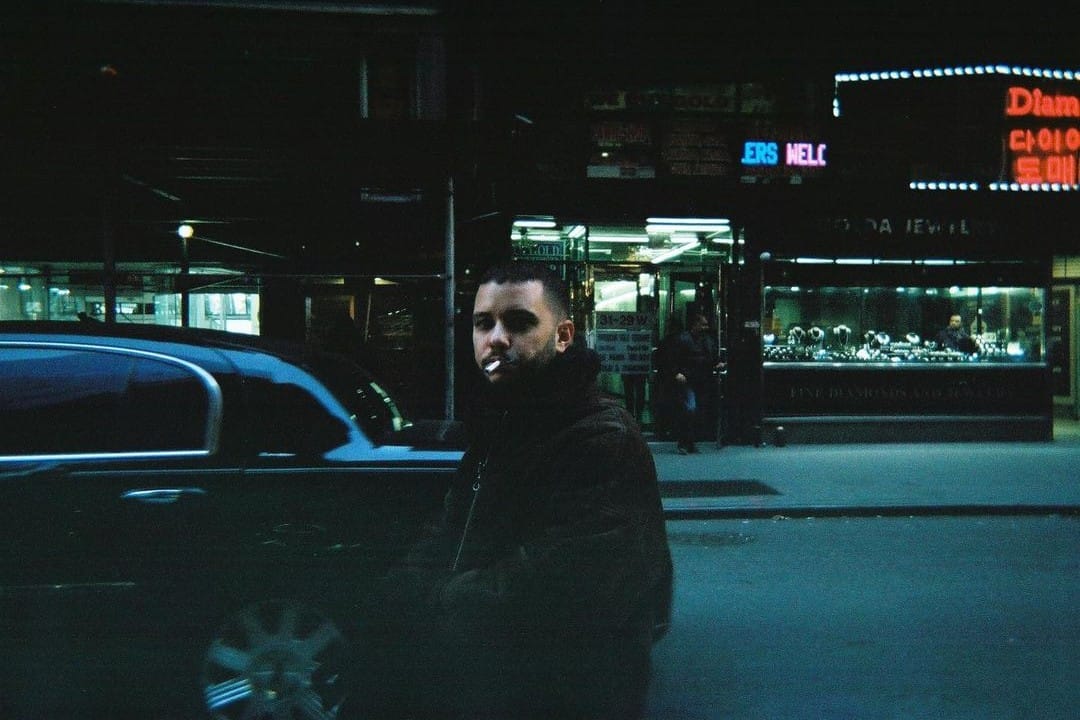 Jimmy Whoo caminando en una calle con un abrigo puesto