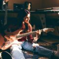 Rafaela Riboty sentada en el suelo de su estudio casero con una guitarra