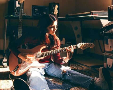 Rafaela Riboty sentada en el suelo de su estudio casero con una guitarra