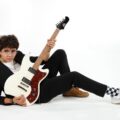 Luis Sosa recostado en el suelo con su guitarra en la mano