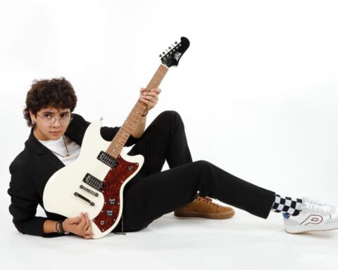 Luis Sosa recostado en el suelo con su guitarra en la mano