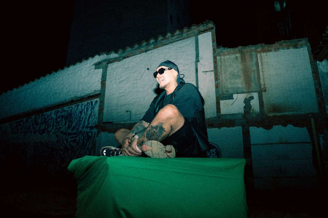 Kriska con lentes de sol sentado entre viviendas