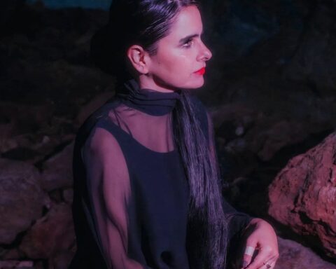 Sofia Kourtesis con un traje negro sobre unas rocas