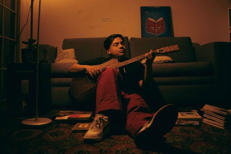 Tate tocando la guitarra sentado en su habitación