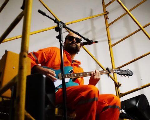Dani Bande con traje naranja y su guitarra en mano