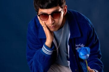 Just River con una casaca azul sosteniendo una flor azul