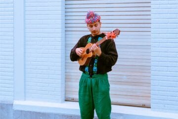 Susobrino tocando un charango vestido de negro y verde