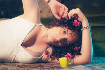 Arantxa recostada con una rosa en el cabello