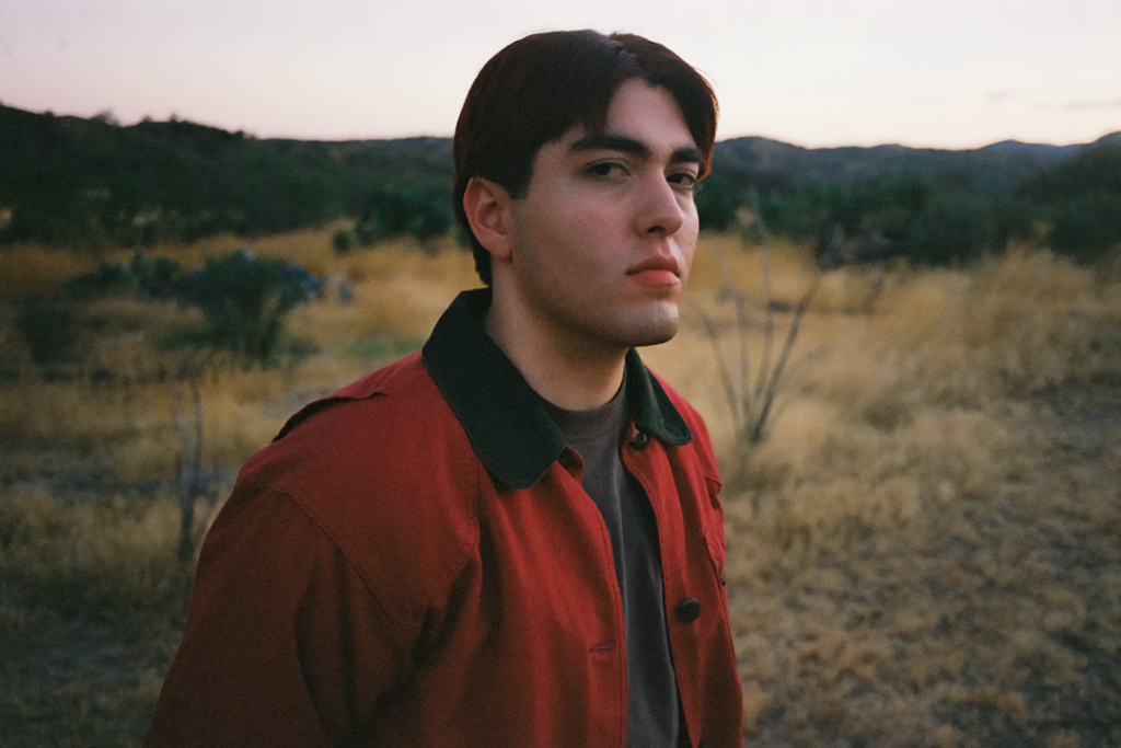 Kevin Kaarl con una chaqueta roja y un pastizal detrás