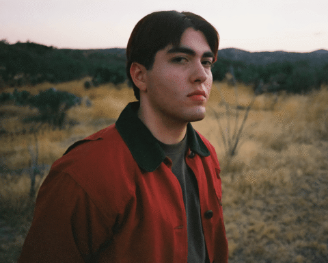 Kevin Kaarl con una chaqueta roja y un pastizal detrás