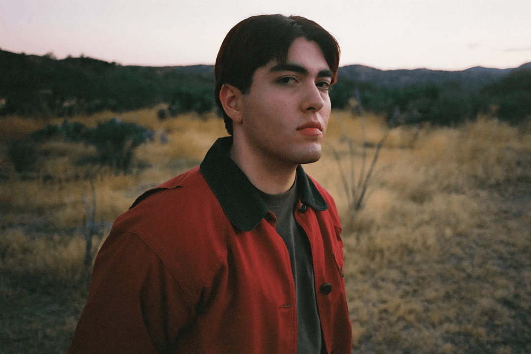 Kevin Kaarl con una chaqueta roja y un pastizal detrás