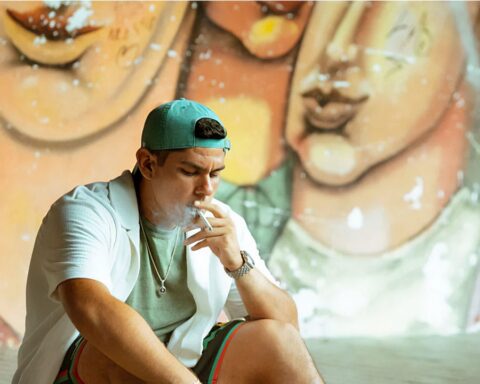 Saldi fumando con un graffitti detrás