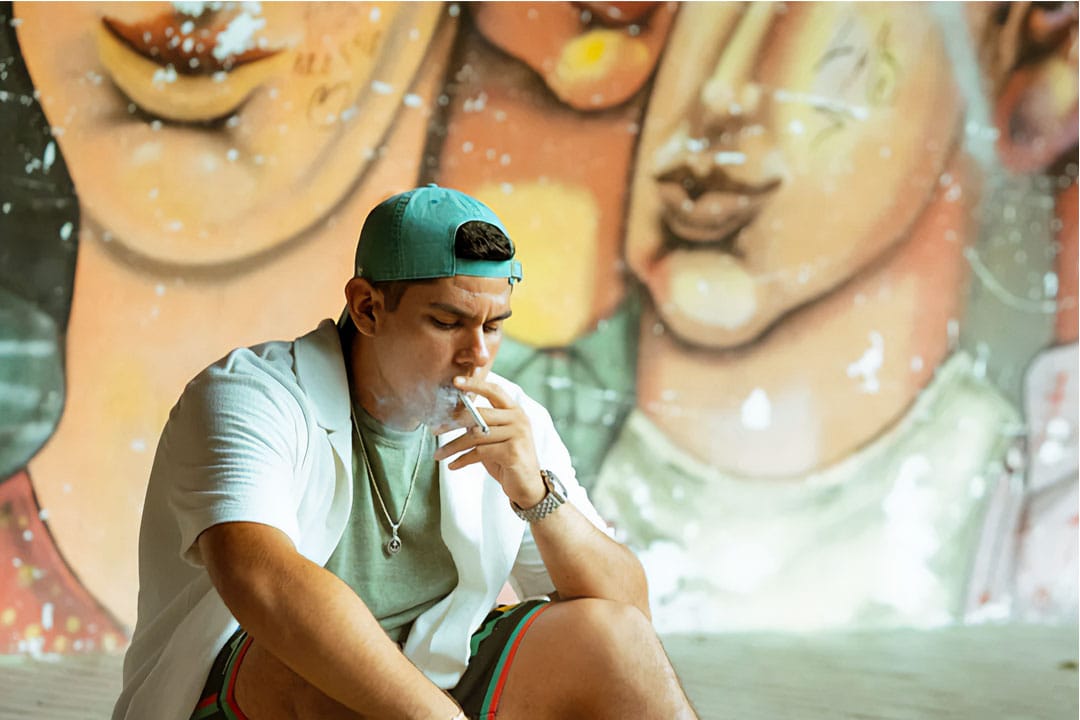 Saldi fumando con un graffitti detrás