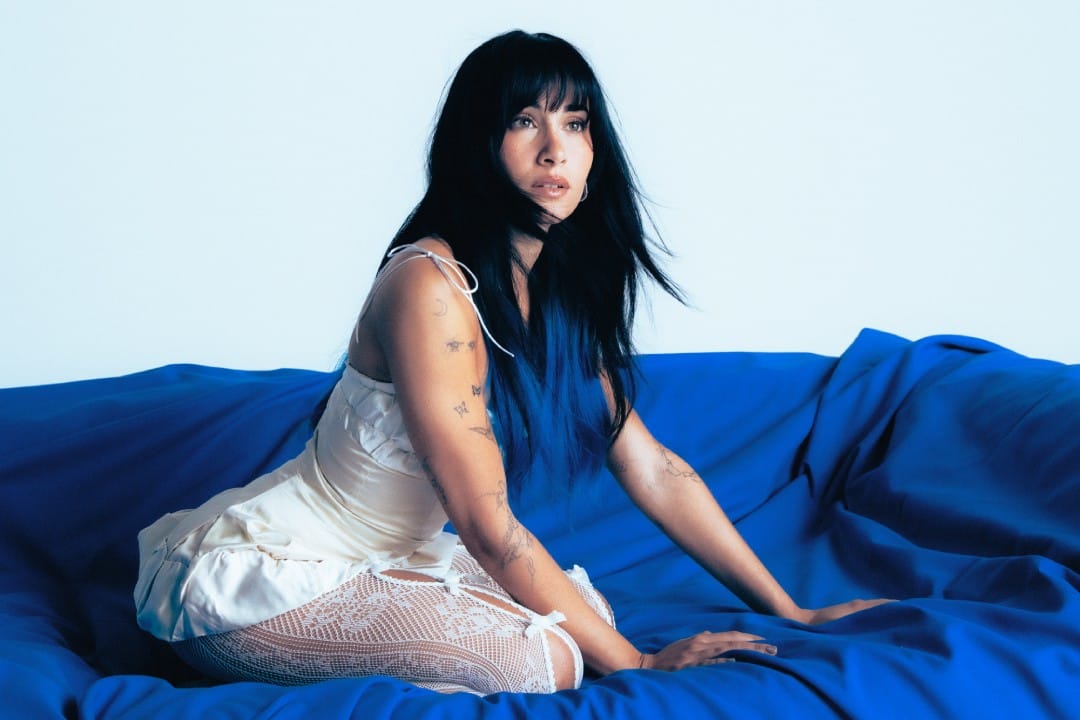 Aitana sobre una cama azul