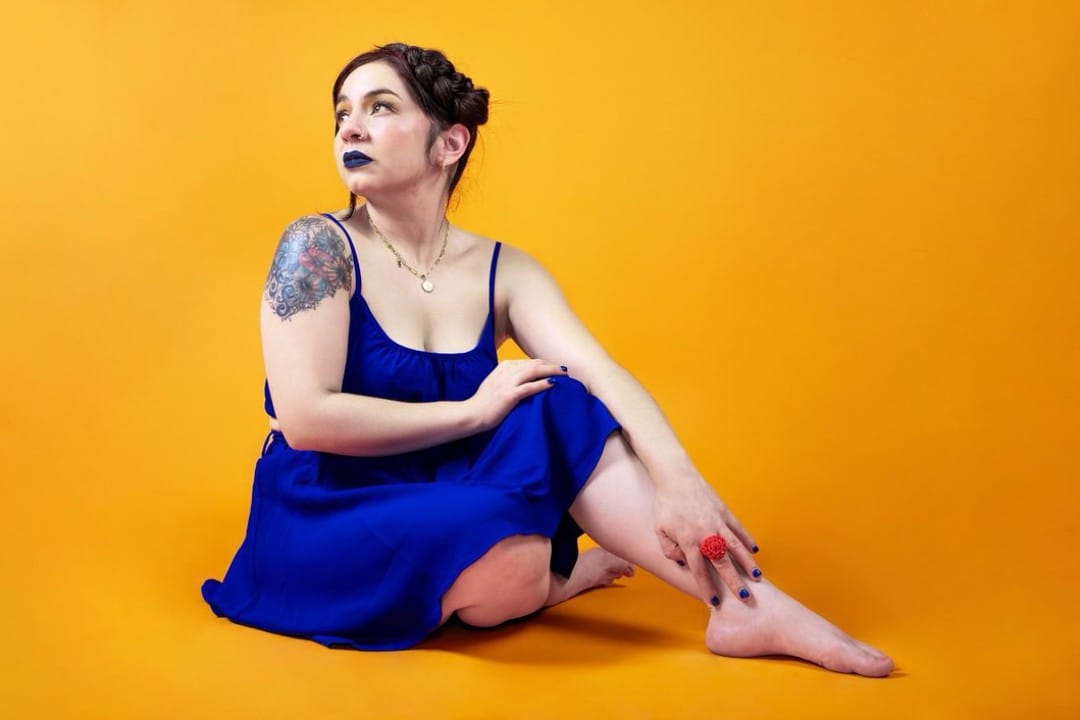 Amanda Tovalin vestida de azul con un fondo amarillo