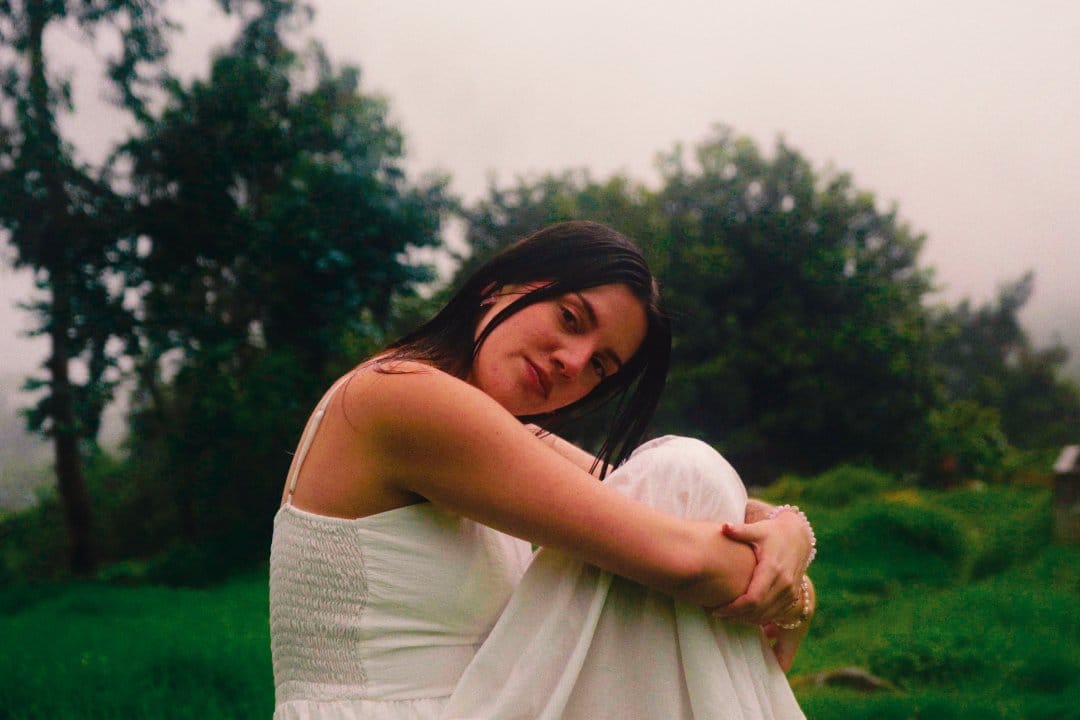 Belu con vestido blanco sentada en un bosque