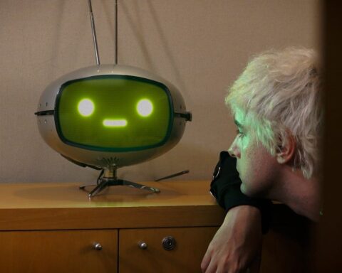 Benito Cerati mirando un robot con pantalla de rostro humanoide