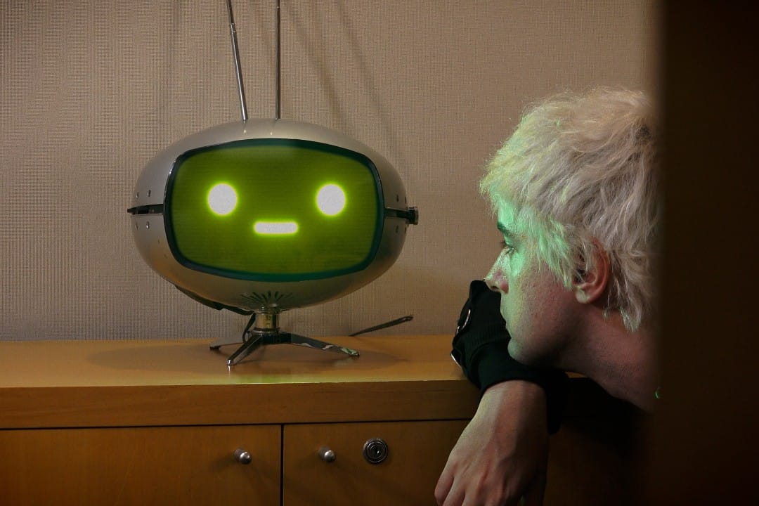 Benito Cerati mirando un robot con pantalla de rostro humanoide