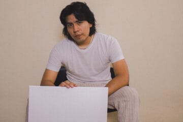 Mial con polo blanco sosteniendo un cartel blanco