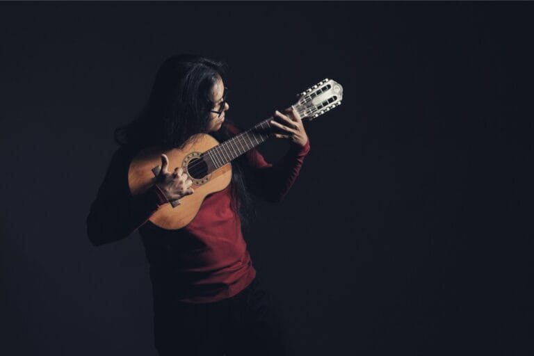 Brageiki de polo rojo tocando de pie su charango