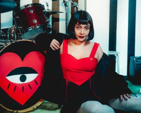 Cancamusa con blusa roja sentada al lado de la batería