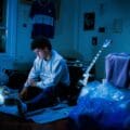 Punto y Pacífico en su habitación con su laptop y su guitarra