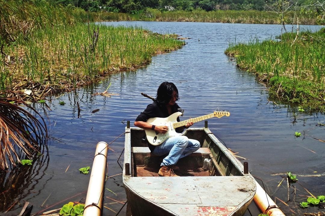 Wayku en un bota de la Amazonía con su guitarra