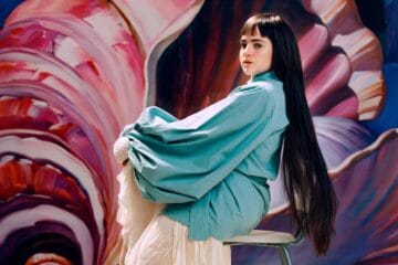 Camille Jackson posando sobre una silla y con un fondo pastel