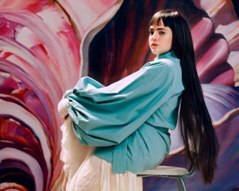 Camille Jackson posando sobre una silla y con un fondo pastel