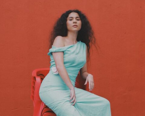 Silvana Estrada en un asiento y pared rojos