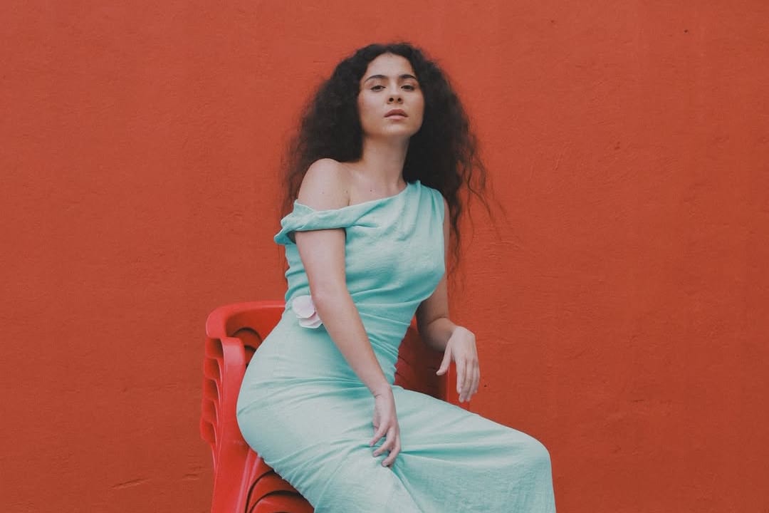 Silvana Estrada en un asiento y pared rojos