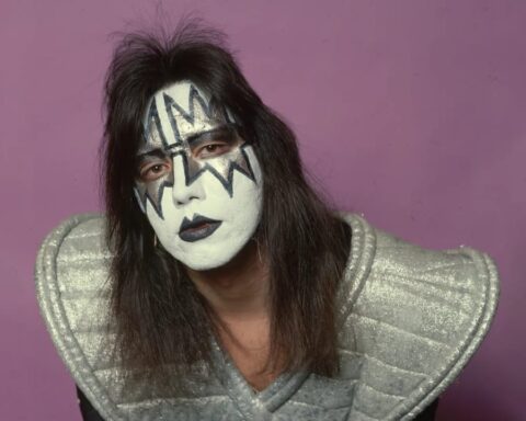 Ace Frehley posando en fondo rosa con traje de Kiss