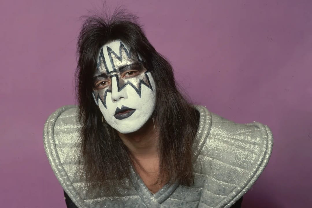 Ace Frehley posando en fondo rosa con traje de Kiss