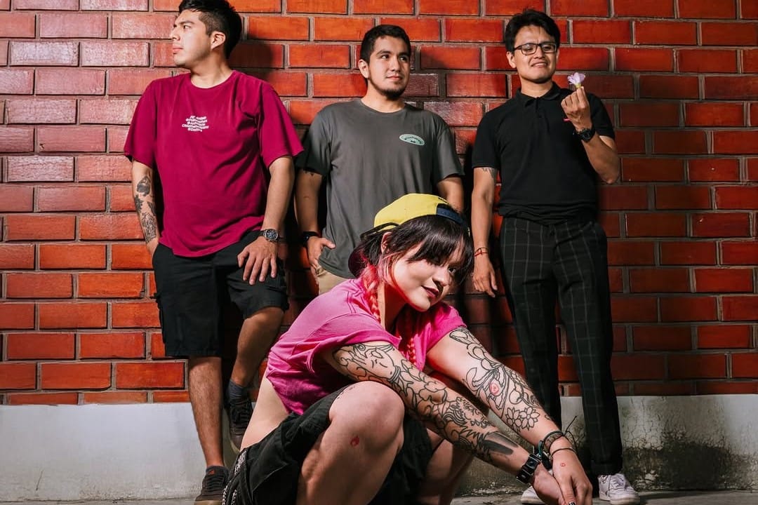 Caos en Primavera posan frente a una pared de ladrillos