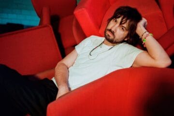 Kevin Parker de Tame Impala sobre un sofá rojo