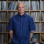 Flea con un estante de vinilos detrás