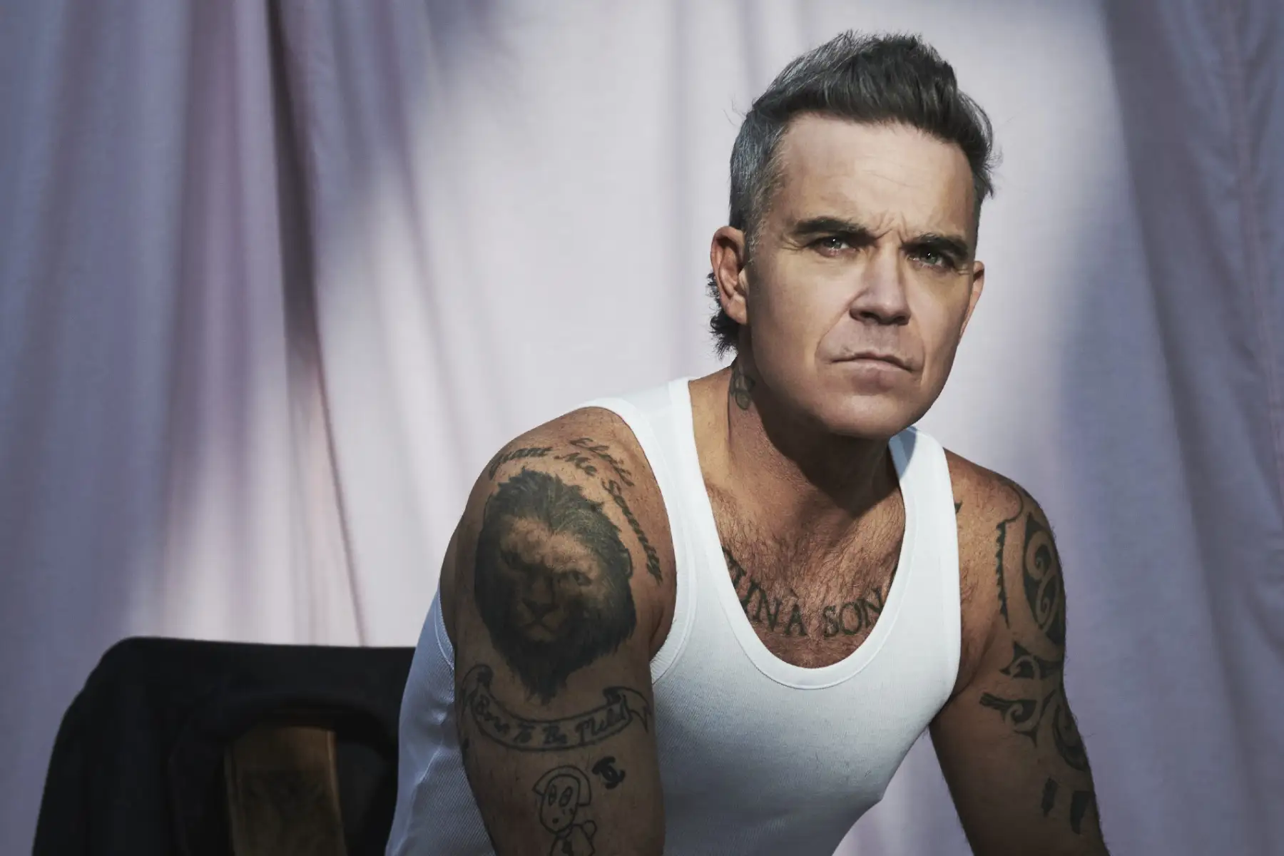Robbie Williams sentado con un bividi