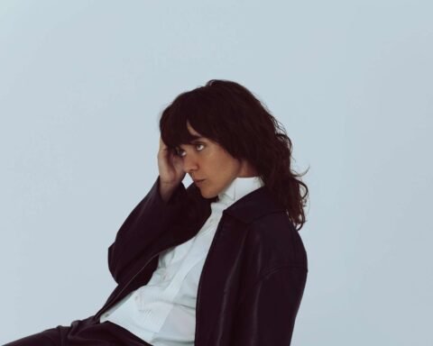 Courtney Barnett con saco negro y sentada