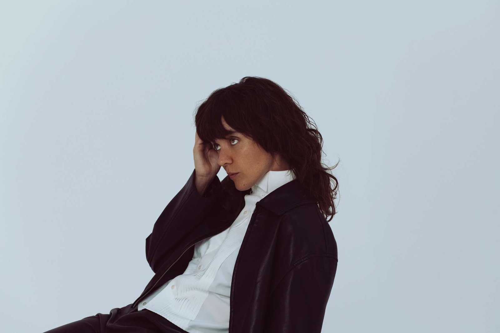 Courtney Barnett con saco negro y sentada