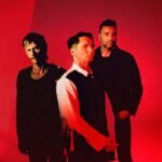 Muse posando con un fondo rojo