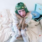 Lolito Sinclair en una cama con un tocadiscos