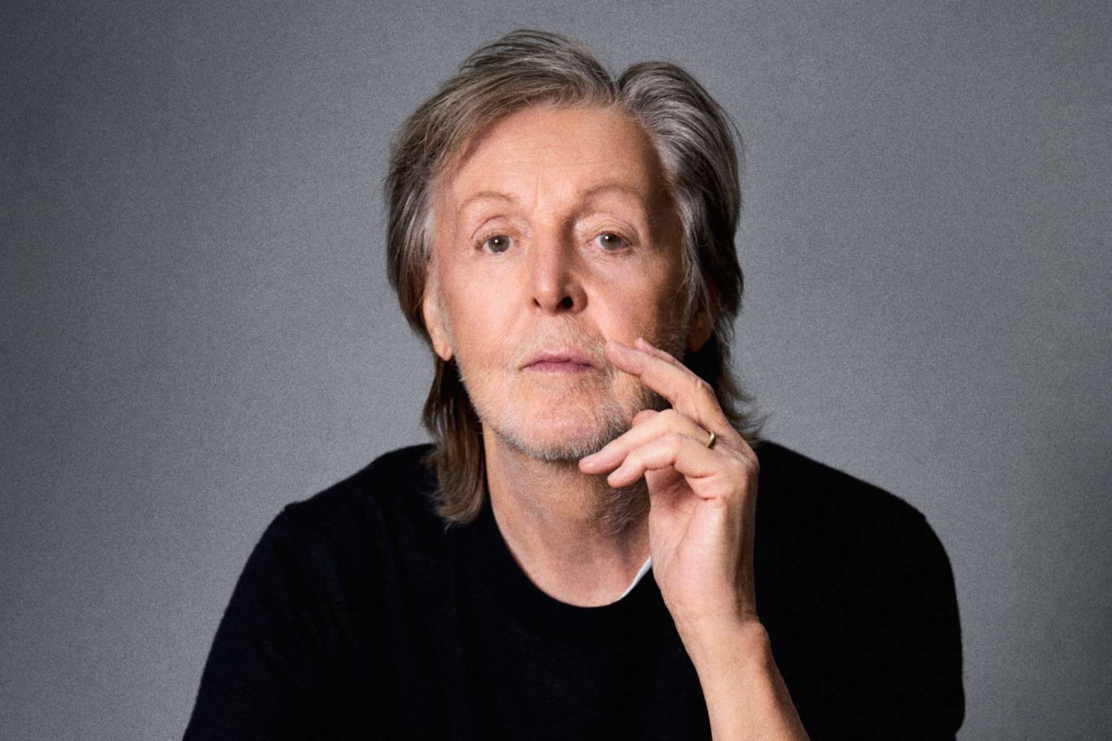 Paul McCartney posando con fondo gris
