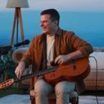 Nahuel Pennisi con su guitarra en una terraza