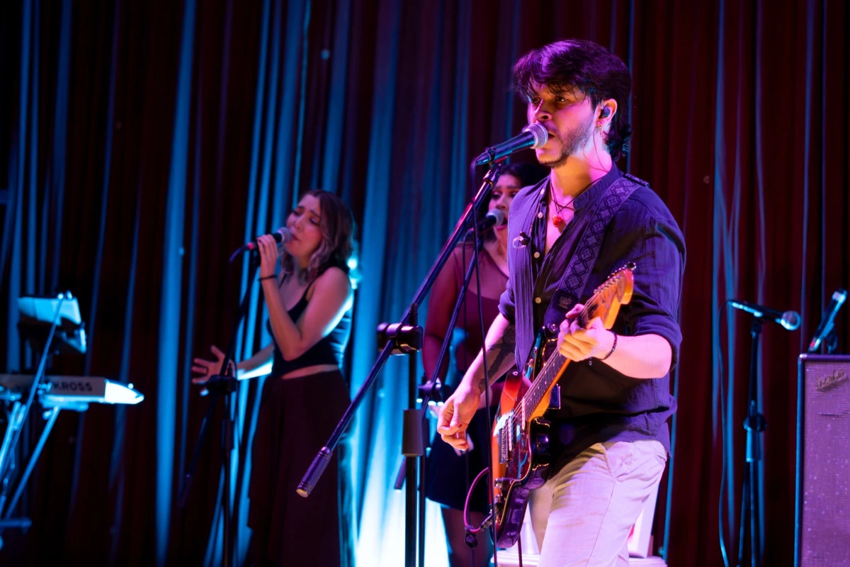 DEBRA en concierto, con un guitarrista y cantante frente al micrófono